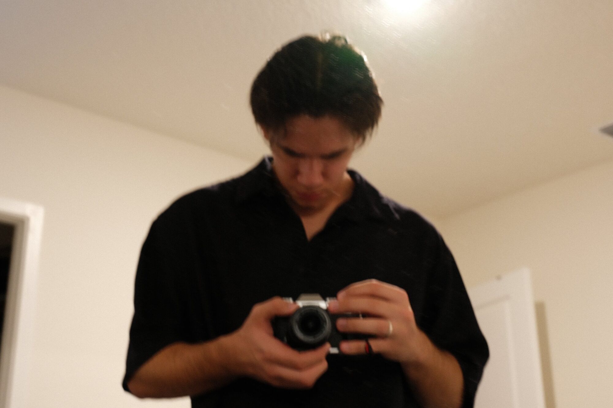 Matheus looking down at his Fujifilm camera in a warm-lit room